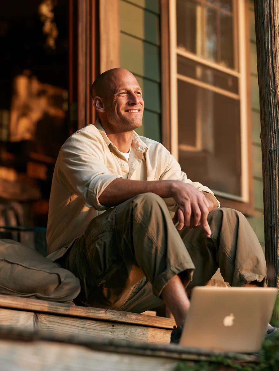 Man completing the Uplyft Capital personal loan application on his laptop from a wooden porch