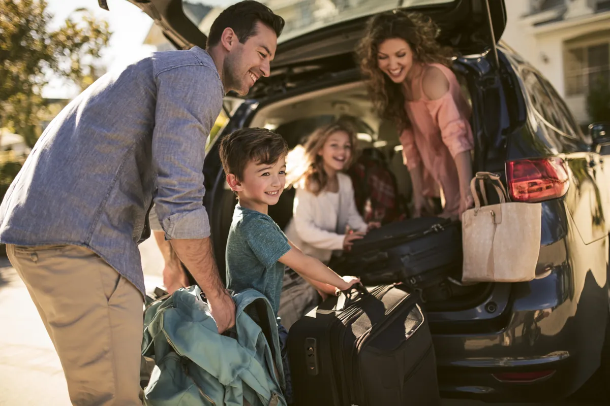 Family loading luggage into a car trunk for a holiday road trip budgeted with the Uplyft Capital travel worksheet