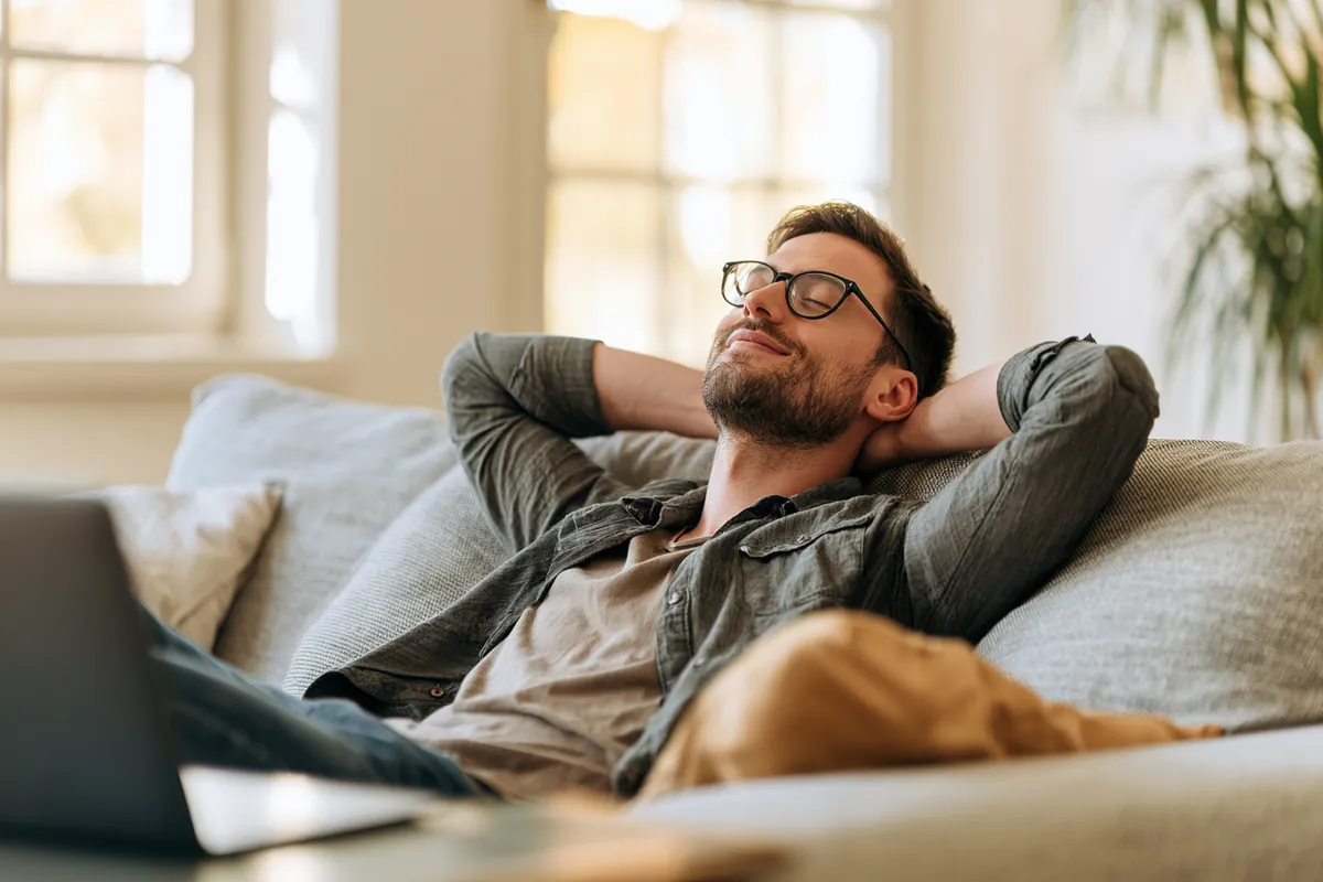 Man on a couch exhaling with relief after consolidating his debt payments with an Uplyft Capital loan